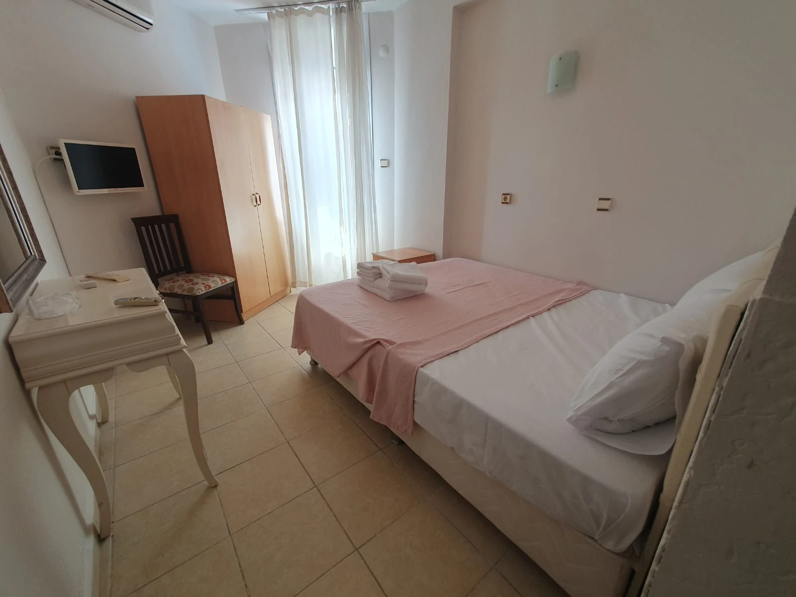 Neşe Hotel Çeşme — Doppelbett mit rosa Überwurf und Kleiderschrank